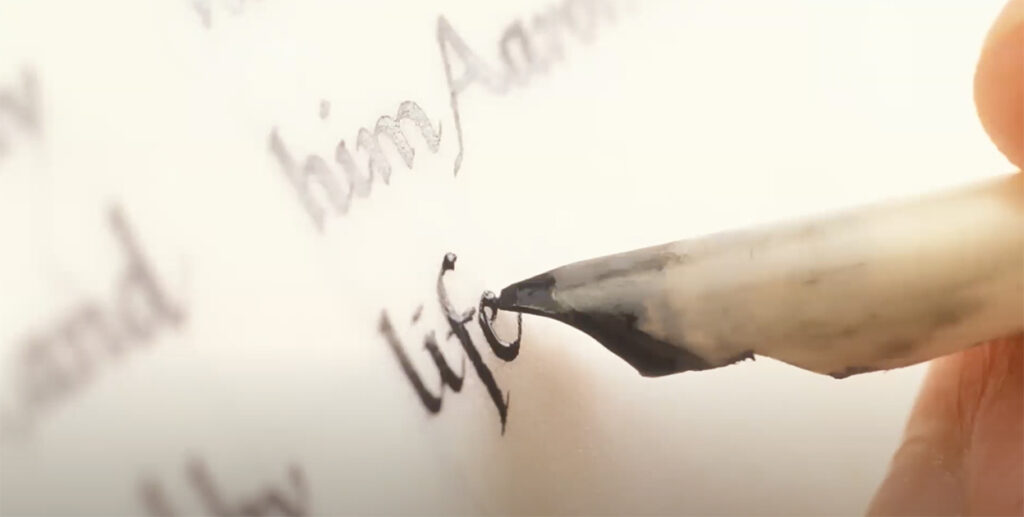 quill scribing ink on paper, the word "life" is written